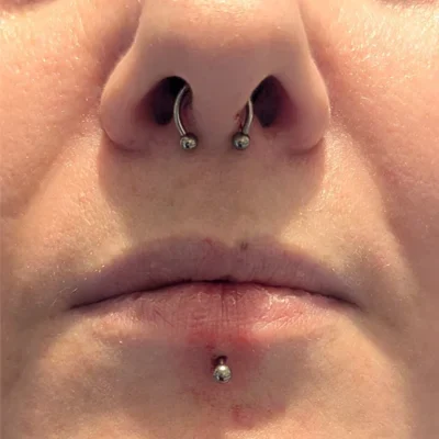 Septum & Labret Piercing Close up of a woman's nose and lips with a septum piercing and labret piercing.